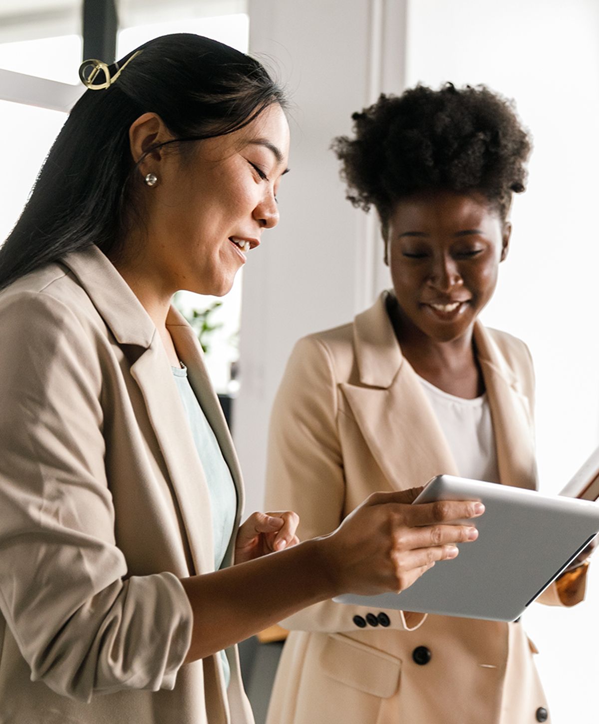Two women collaborating with a tablet in office.