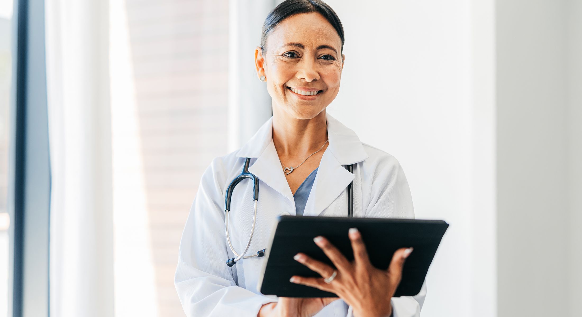 Smiling doctor holding a tablet in office.